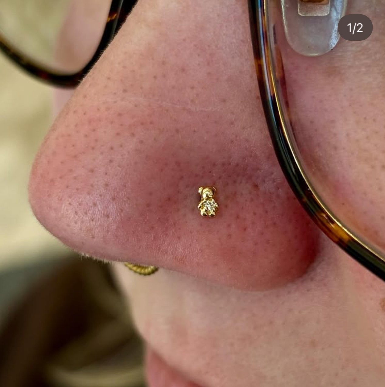 Nostril piercing with tiny gold teddy bear charm