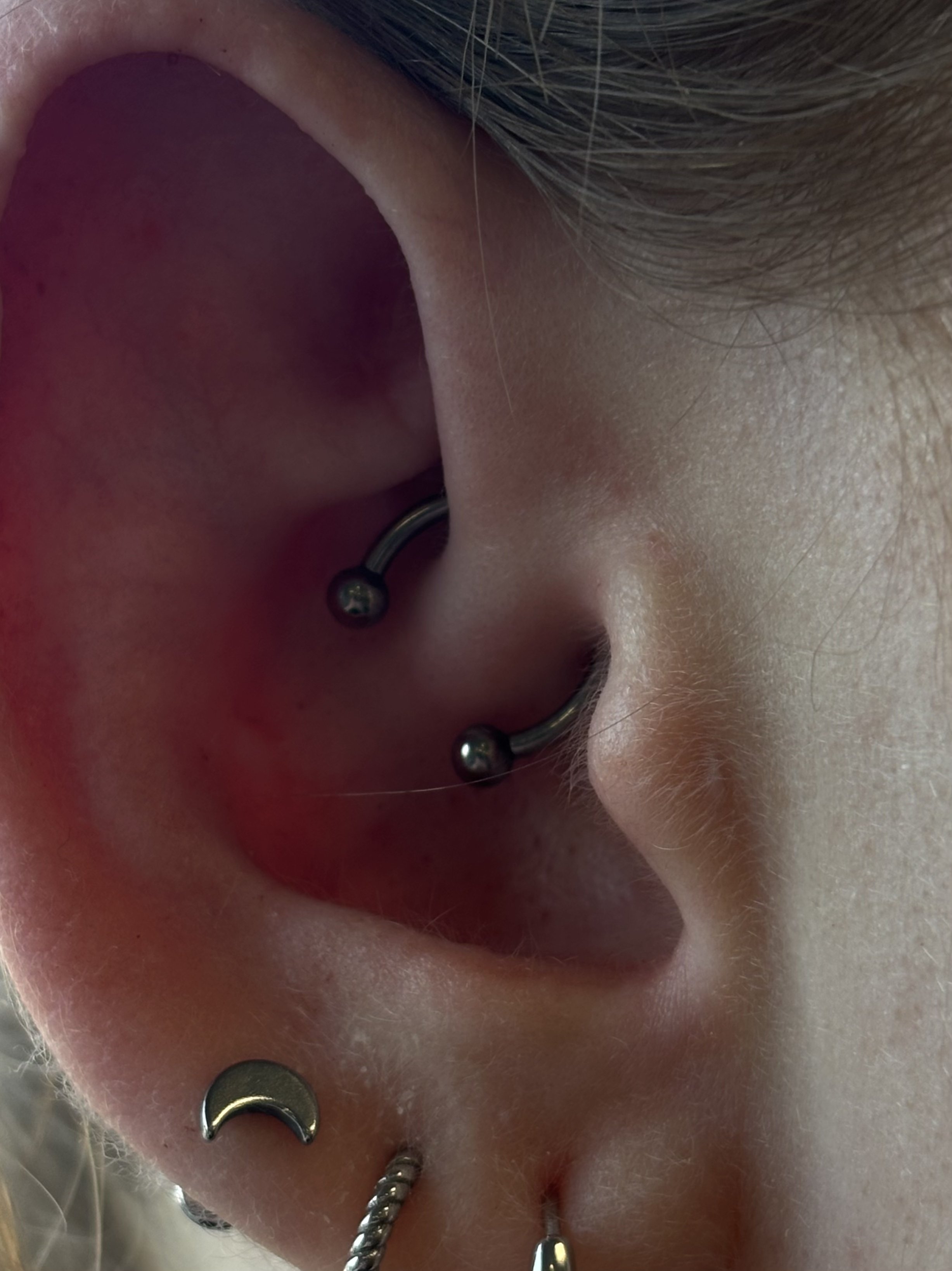 Helix piercings with silver circular barbell in conch and gold crescent moon hoop in lobe