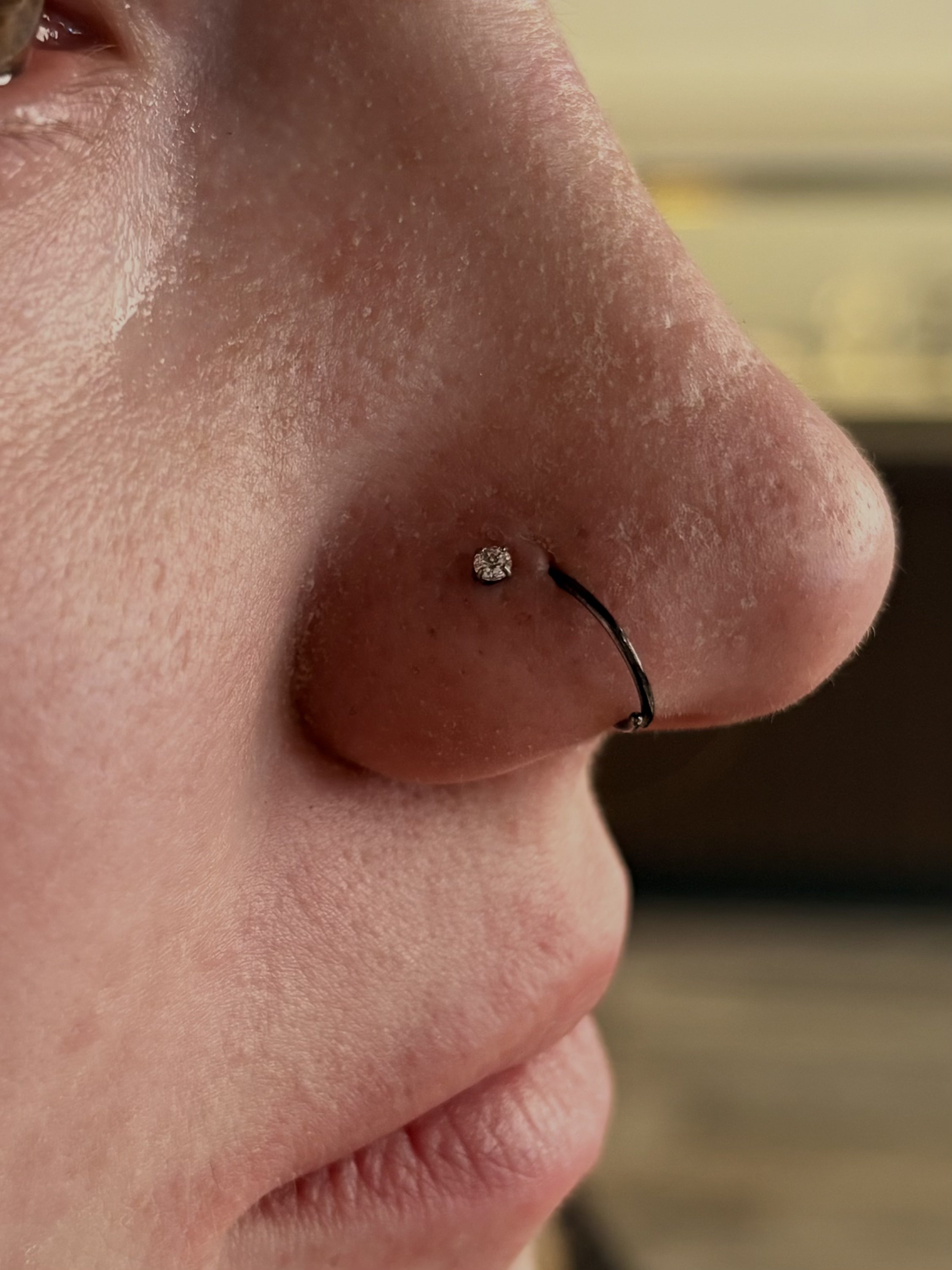 Nostril piercing with crystal stud and black hoop ring