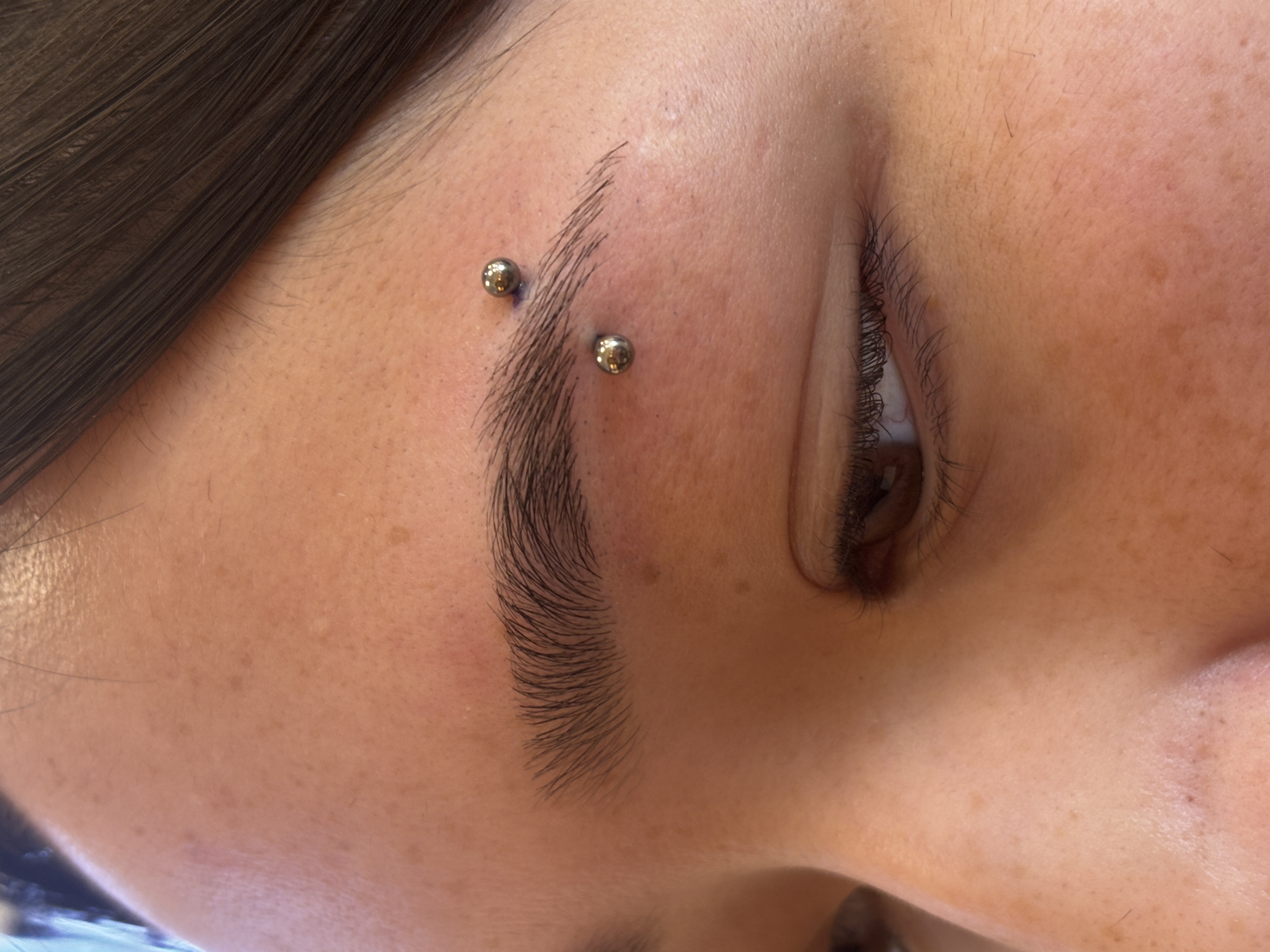 Eyebrow surface piercing with titanium balls