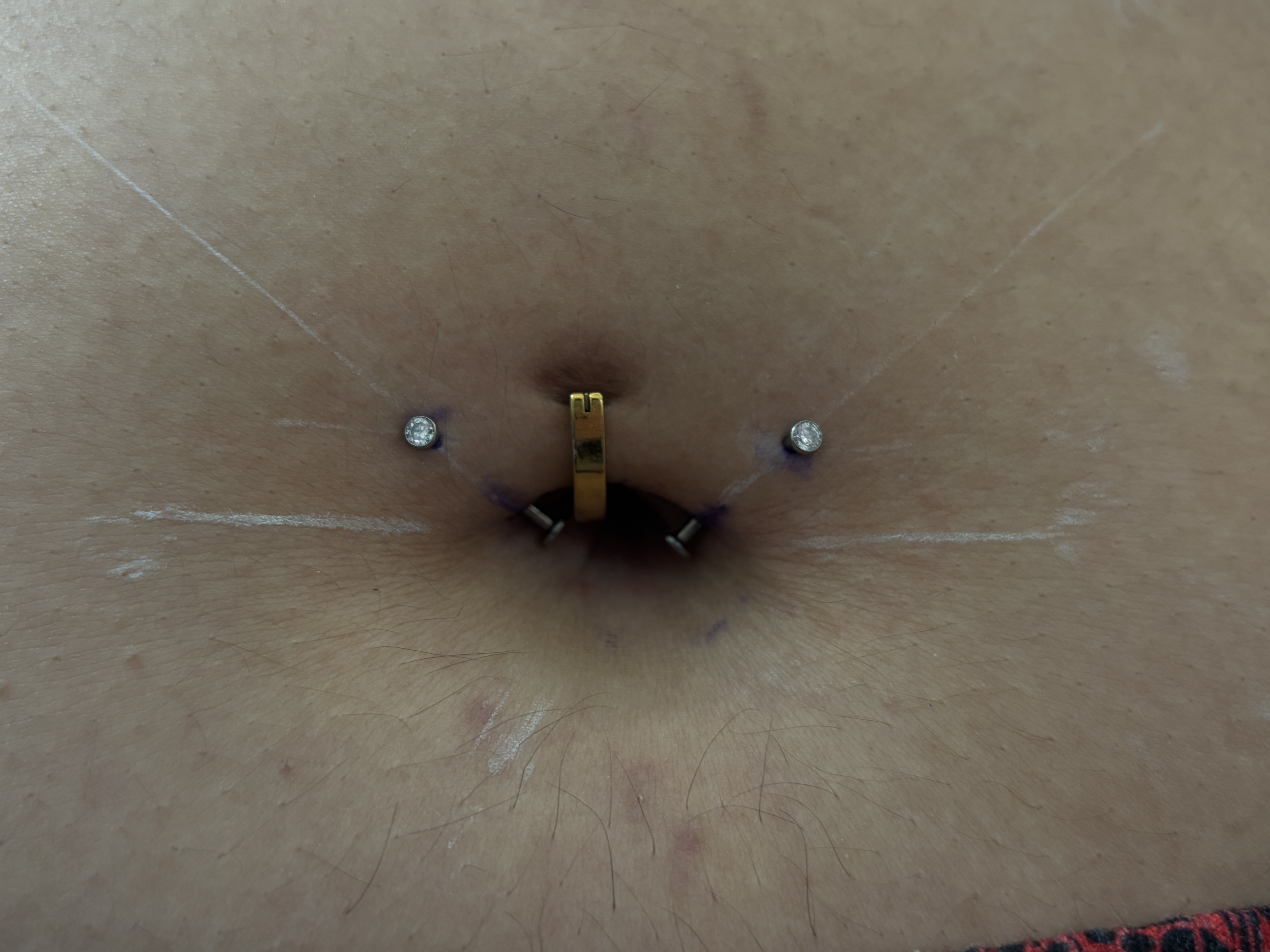 Navel area piercings with gold and crystal jewelry