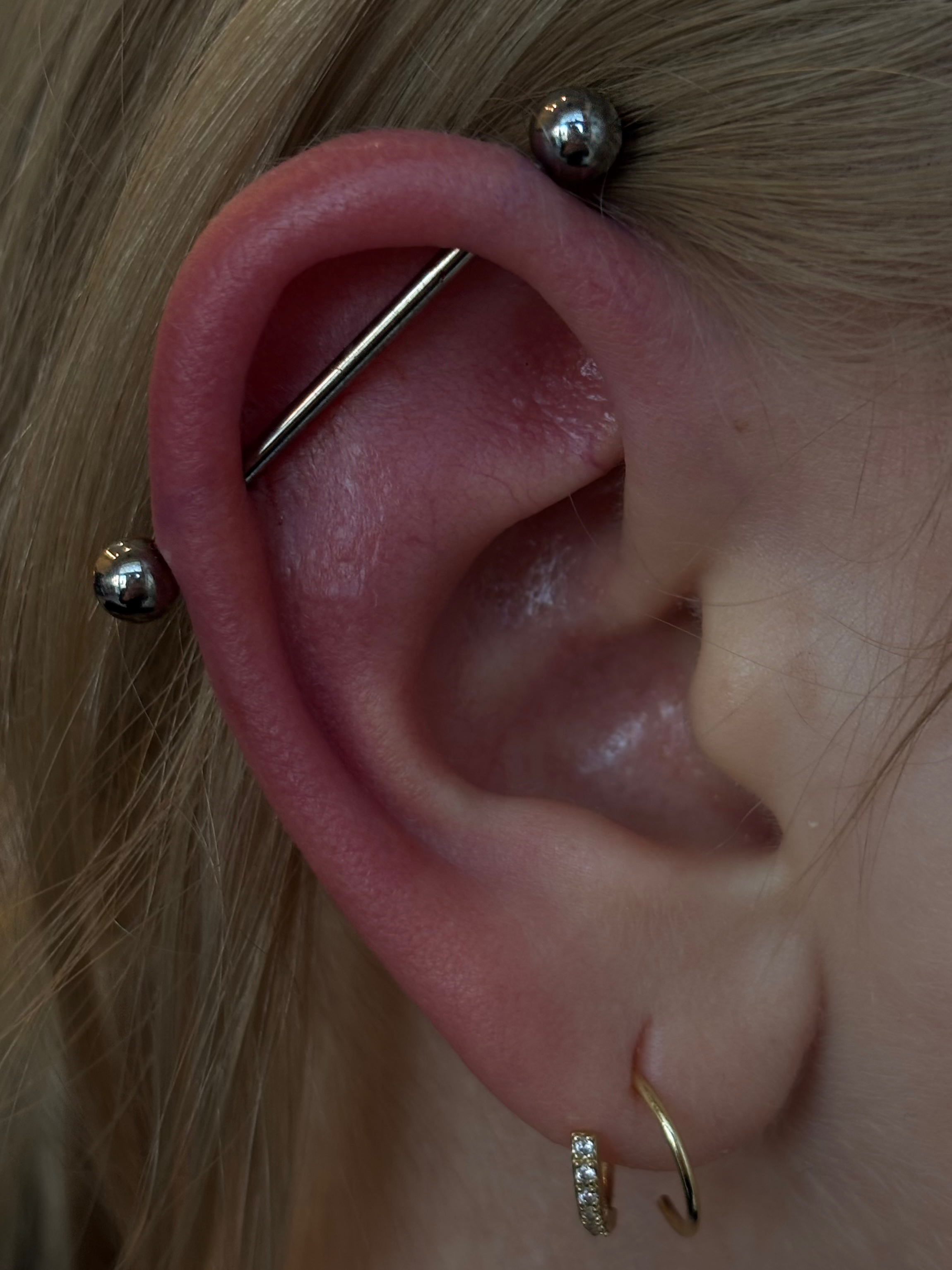 Industrial piercing with titanium barbell and gold crystal huggie hoop in lobe