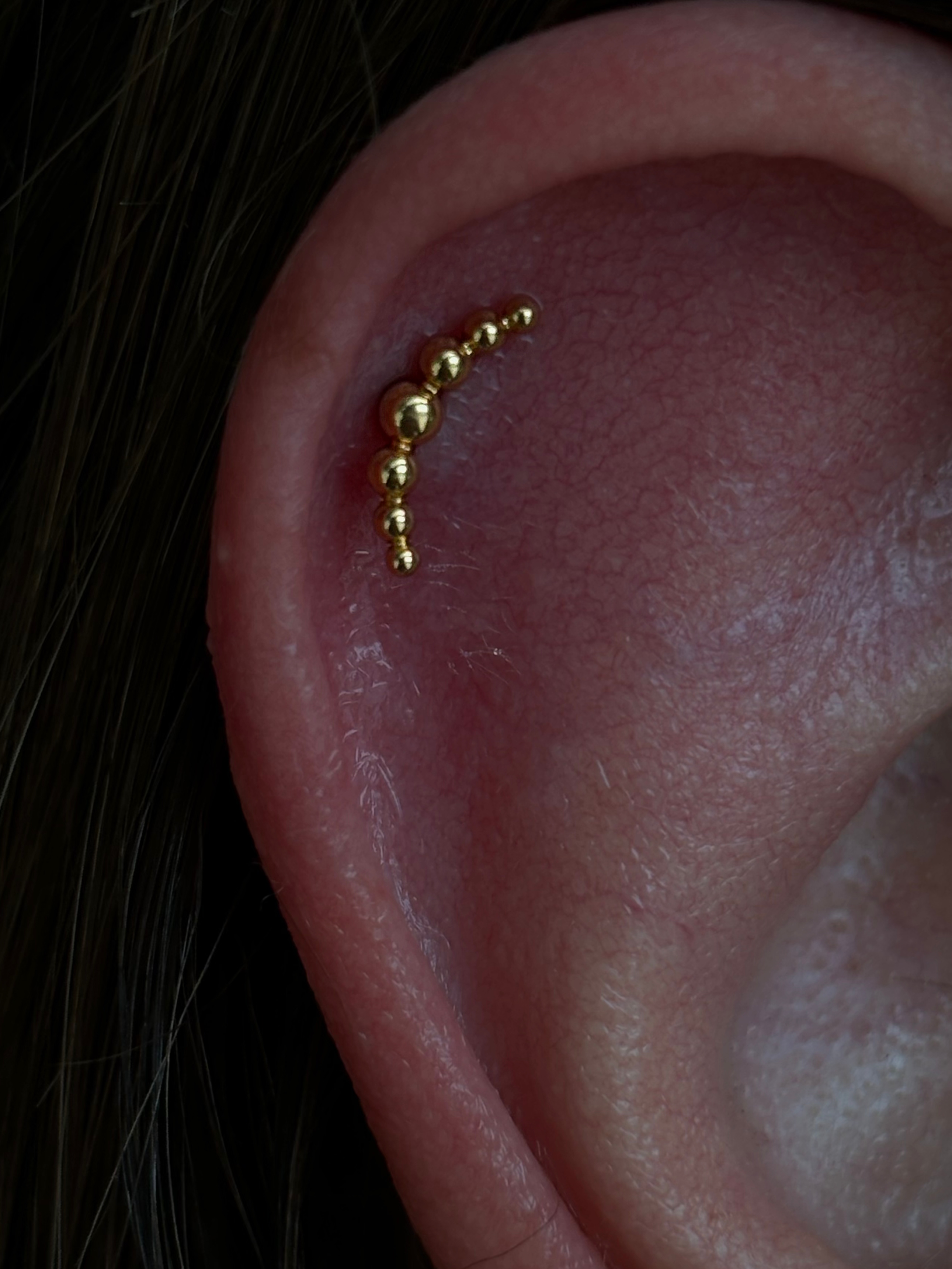 Gold beaded curved piece in upper helix